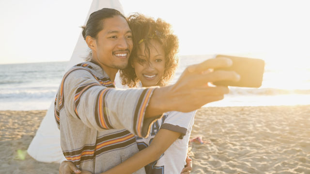 Un couple dans la mer en train de prendre une photo