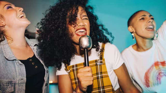 Drei Mädchen singen und lächeln mit strahlend weißen Zähnen